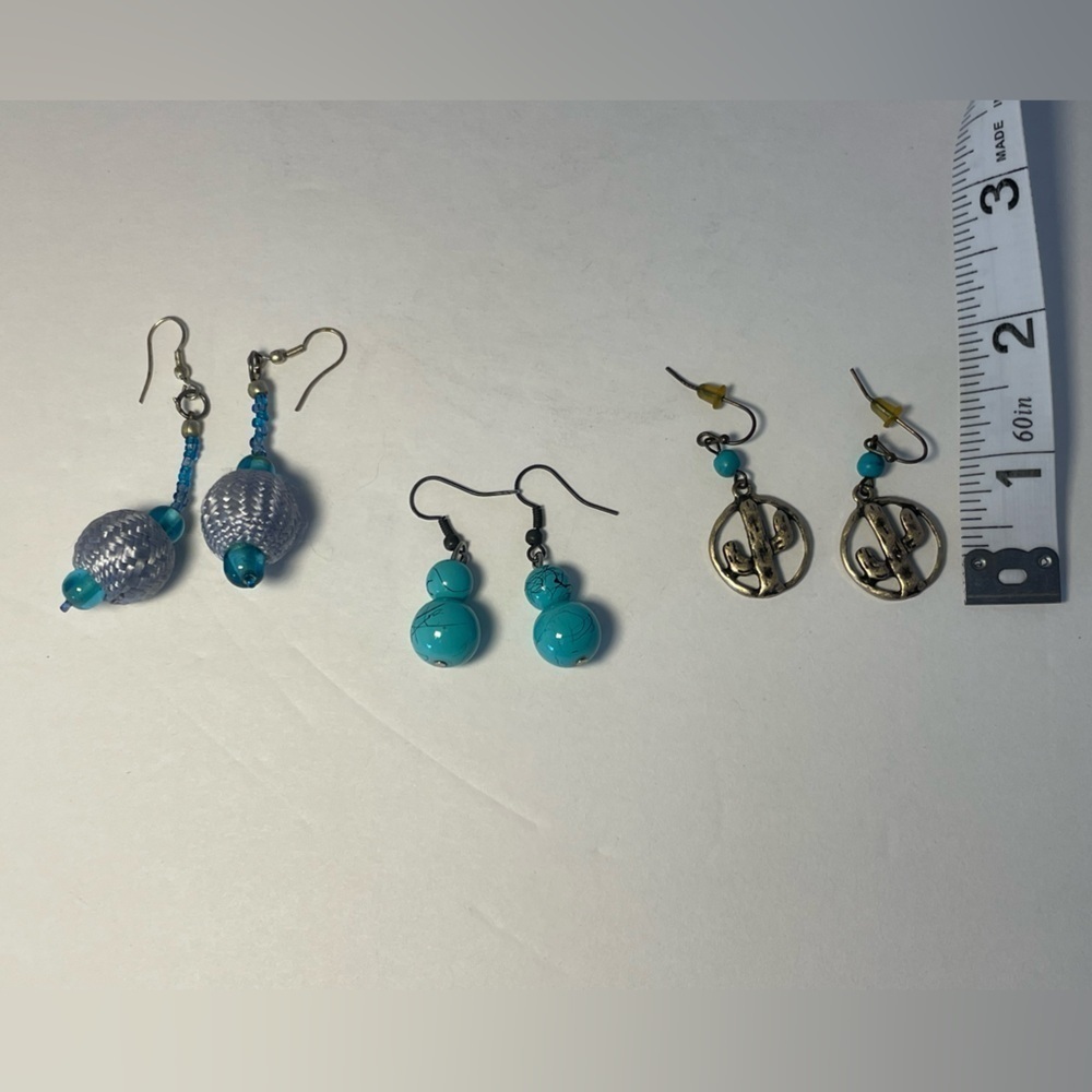 Three pairs of drop earrings with cut out gold cactus and turquoise colors.